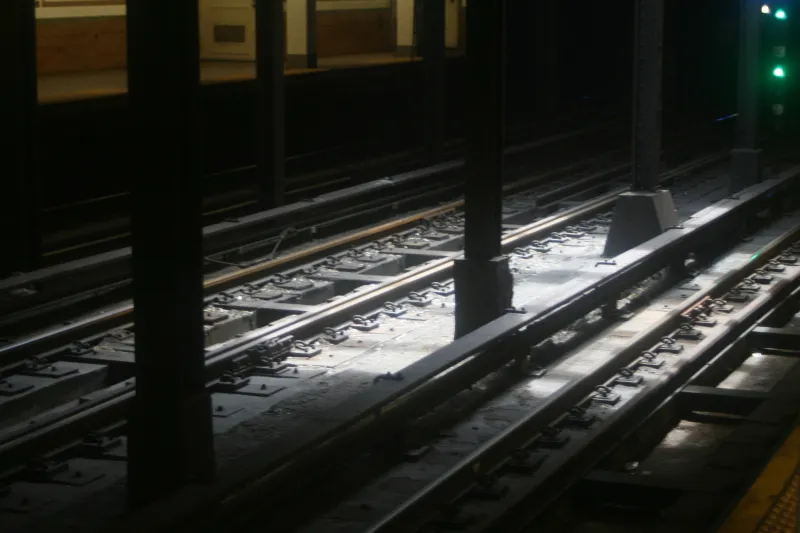 Sunlight falling across the tracks of a dark station