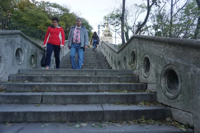 A man and a woman walking down wide stone steps in a park