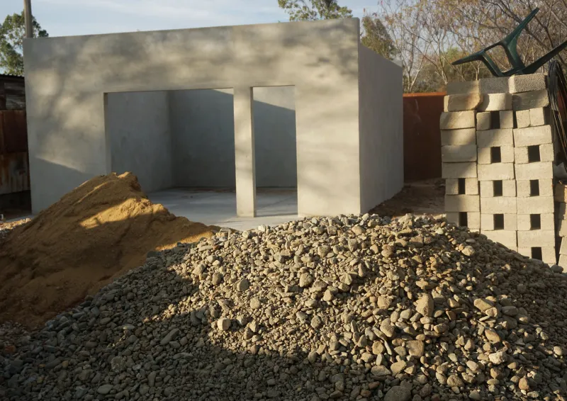 A new concrete building beside a pile of gravel and stacked blocks