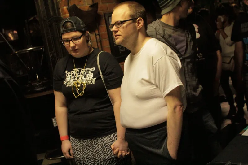 A young couple holding hands in a dark, crowded room