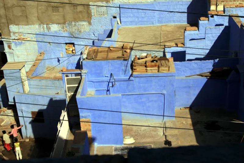 Blue-painted houses seen from above, two children on a rooftop