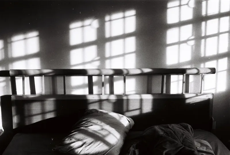 Window light falling across a bed and pillows, in black and white