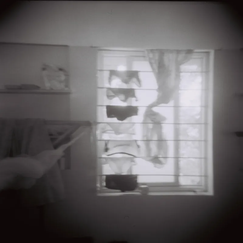 A window with clothes hanging to dry, seen in soft blurred black and white